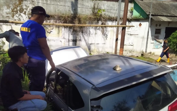 Thumbnail Berita - Mobil Angkutan Online Terperosok di Selokan Jalan Sempit, Damkar Jember Bantu Evakuasi